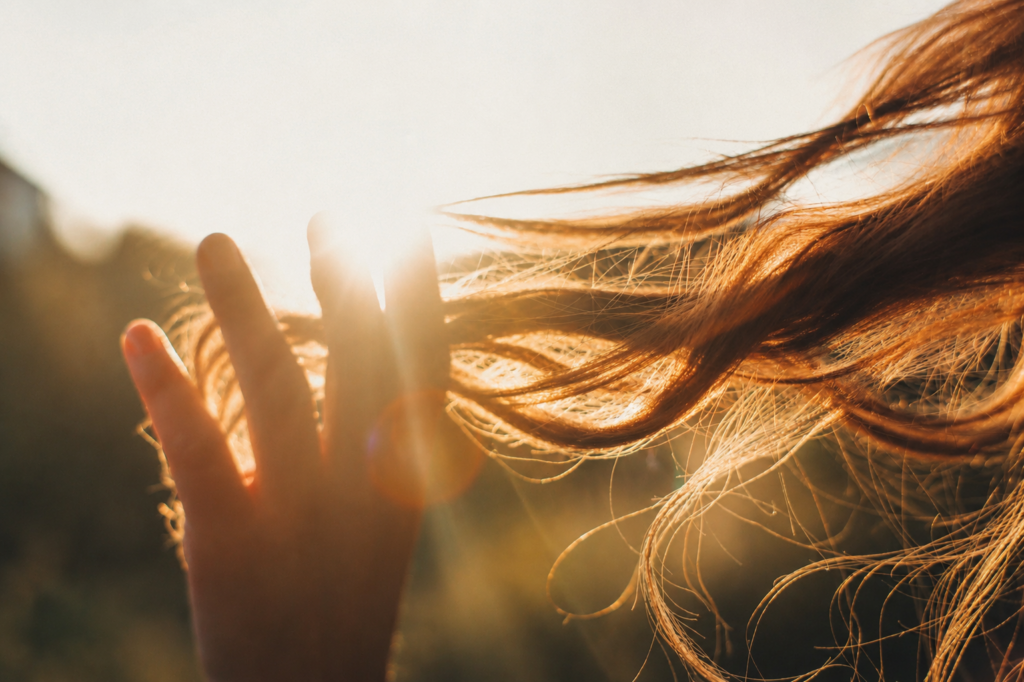 Sunlit hair blowing in the wind, illustrating the effects of UV exposure and environmental stress on hair color and shine.